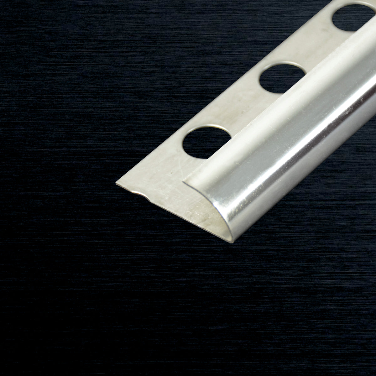 A close-up of a silver metal channel corner bracket with three pre-drilled mounting holes, set against a dark textured background.