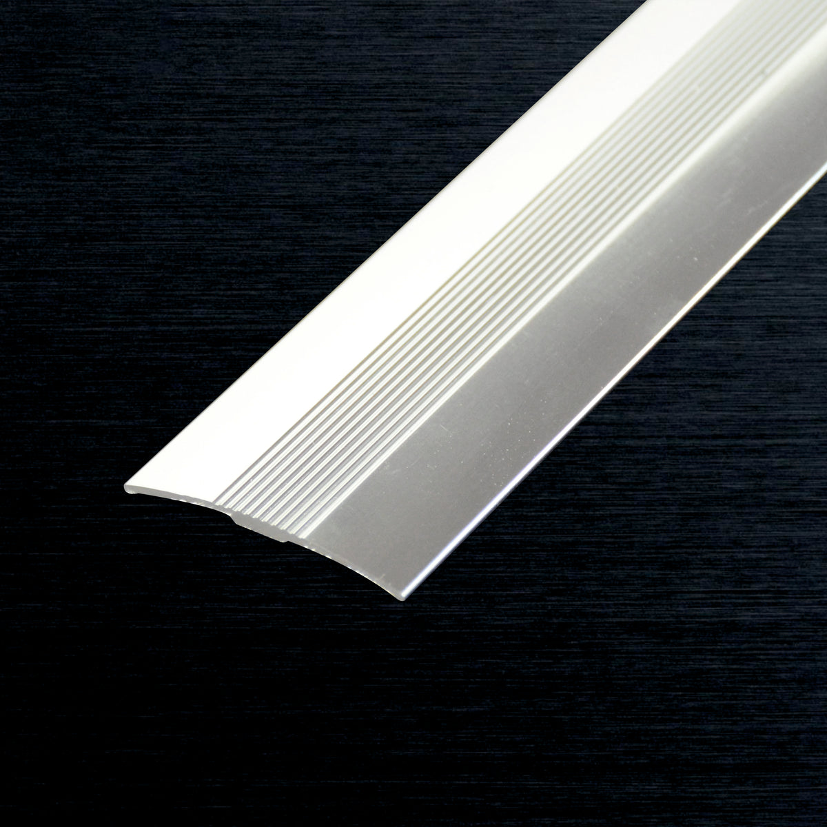 A close-up of a cover strip with a ribbed textured surface, shown diagonally against a dark textured background.