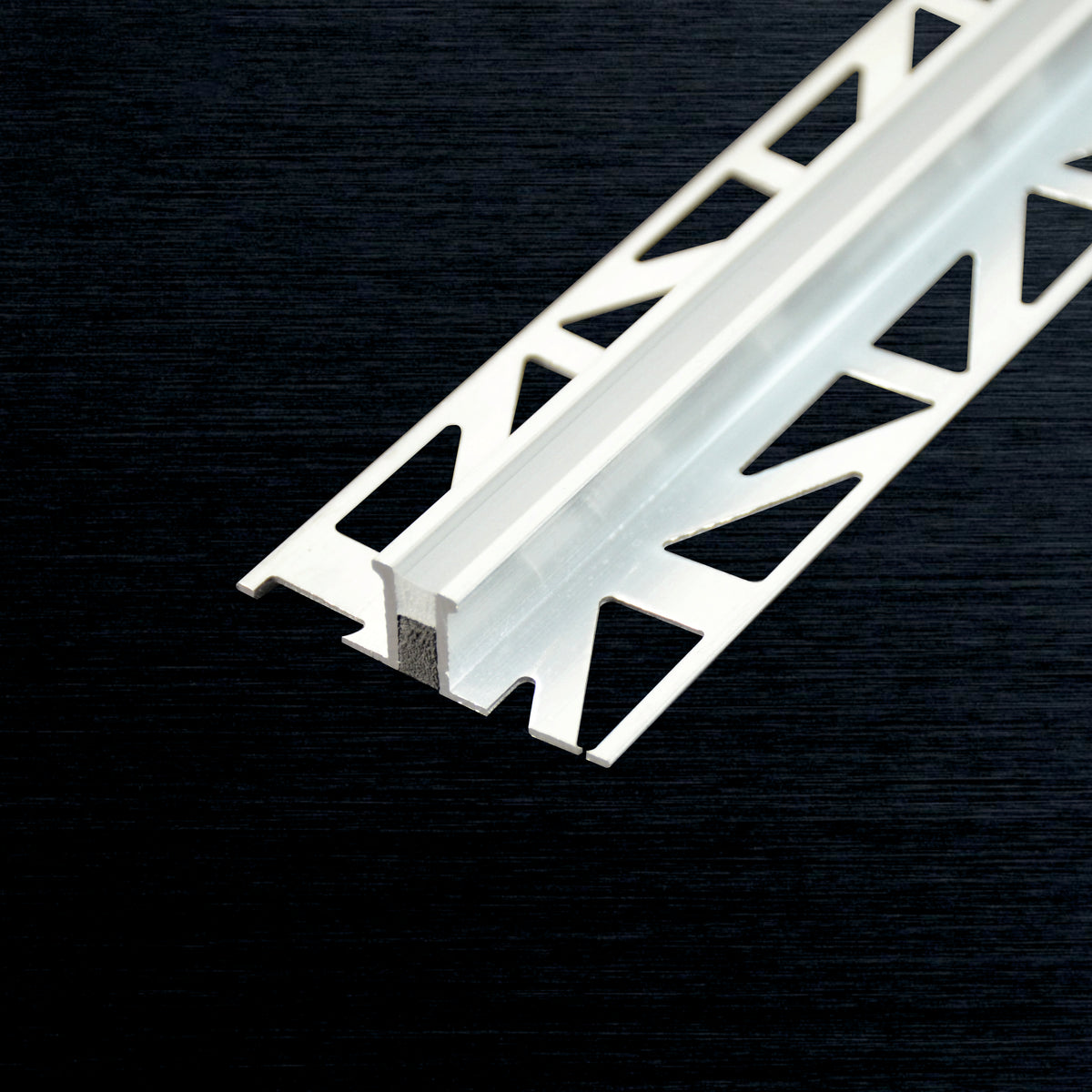A close-up of a expansion joint profile with a triangular lattice cutout pattern, shown diagonally on a dark textured background.