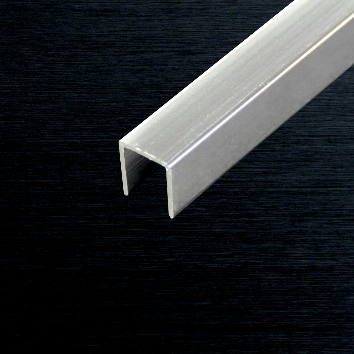 A long, straight silver aluminum U-channel profile tube shown diagonally against a dark textured background.